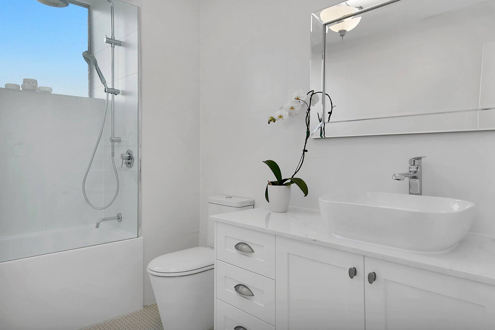 Bathroom after: large white tiles, shaker vanity, vessel basin and frameless screen