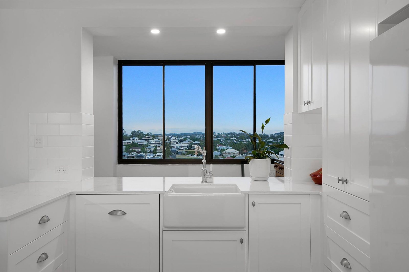 Kitchen after: white shaker cabinetry, stone benchtop and butler's sink under the same window