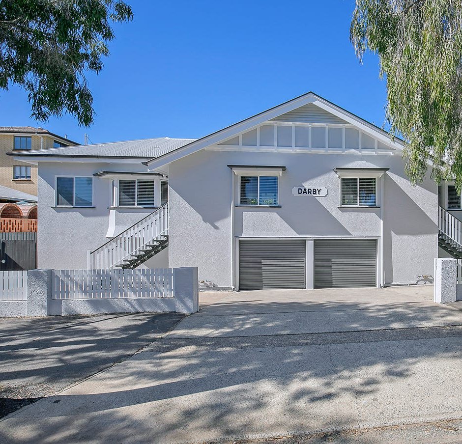 The house after: fresh white render, new white stairs, garage doors and fencing