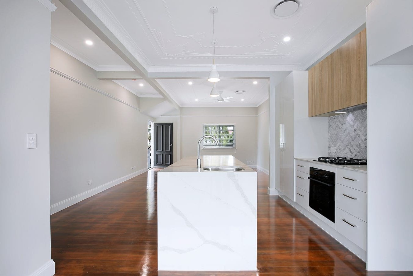 Open-plan kitchen with waterfall stone island and polished timber floors