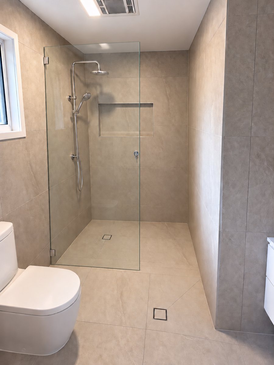 Ensuite after: large-format tiles, frameless shower screen, niche and rail shower