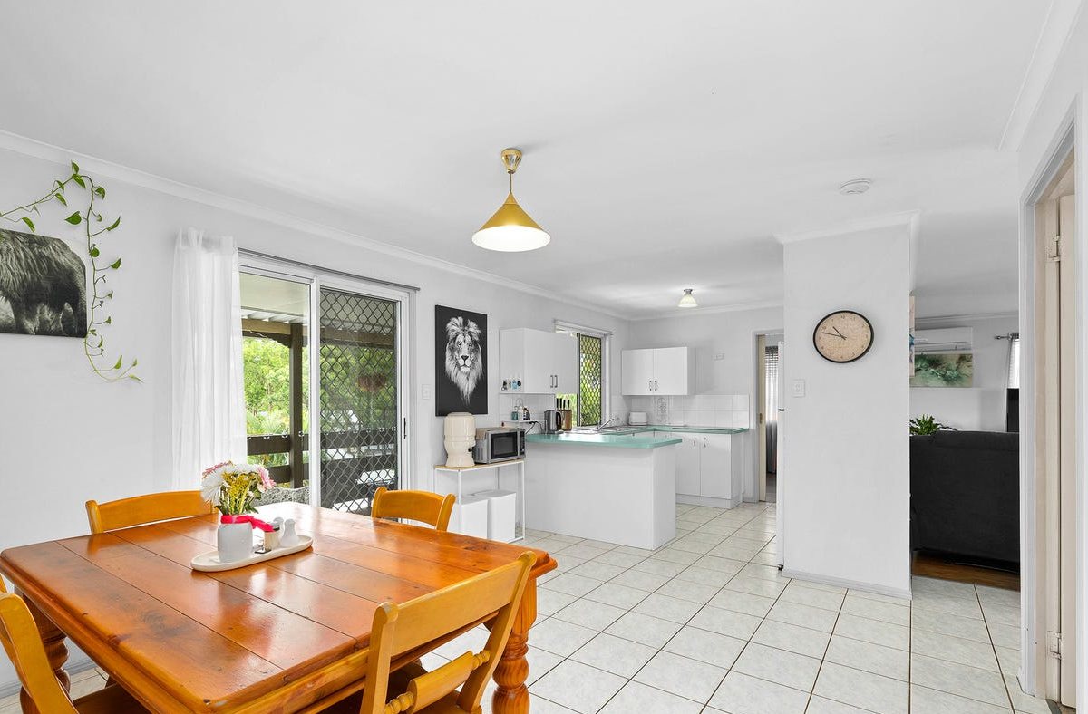Dining and kitchen before: cream floor tiles and a small kitchen with teal benchtops