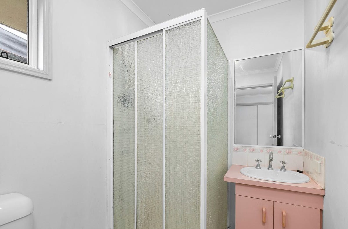 Ensuite before: framed shower cubicle and pink vanity