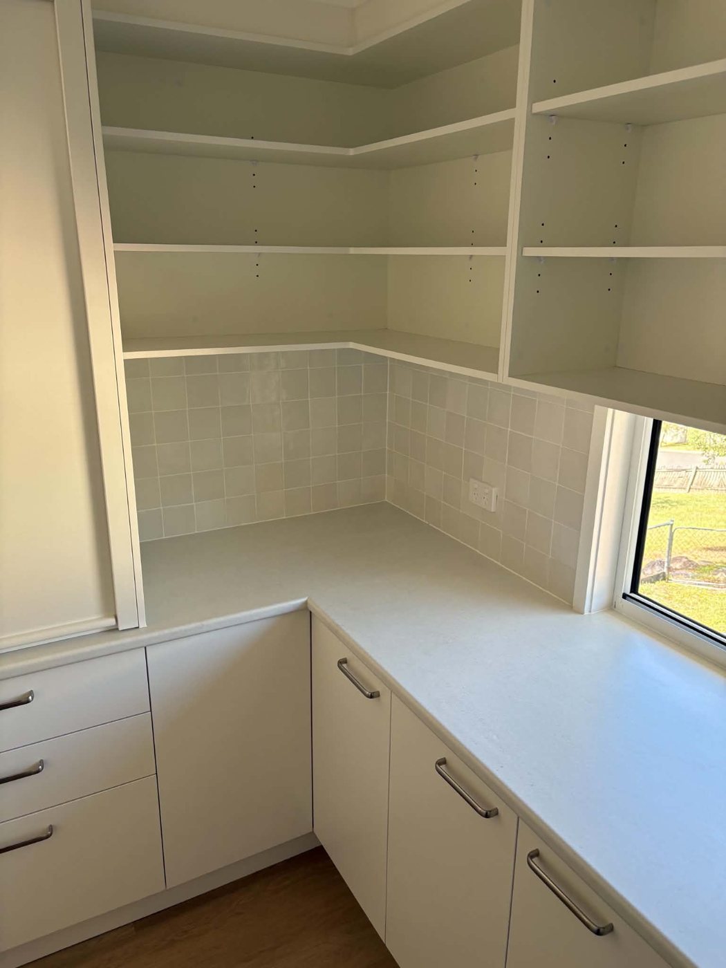 Butler's pantry with adjustable shelving, square tile splashback and window