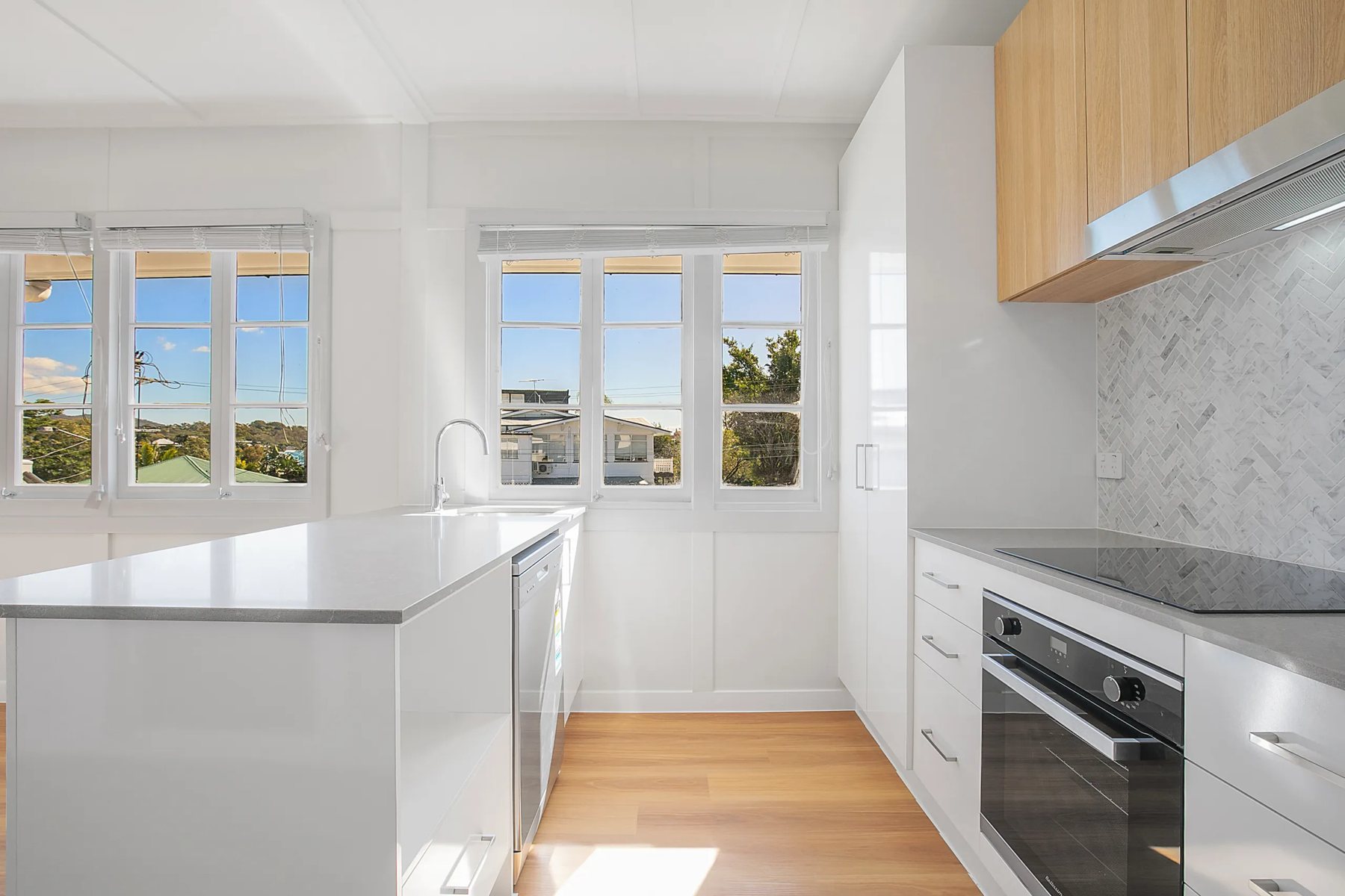 Kitchen with timber-look overheads, herringbone splashback and casement windows