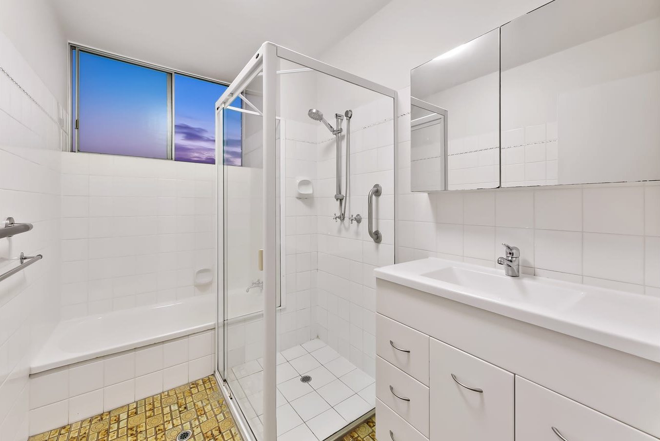 Bathroom before: dated tiles, framed shower screen and patterned floor tiles