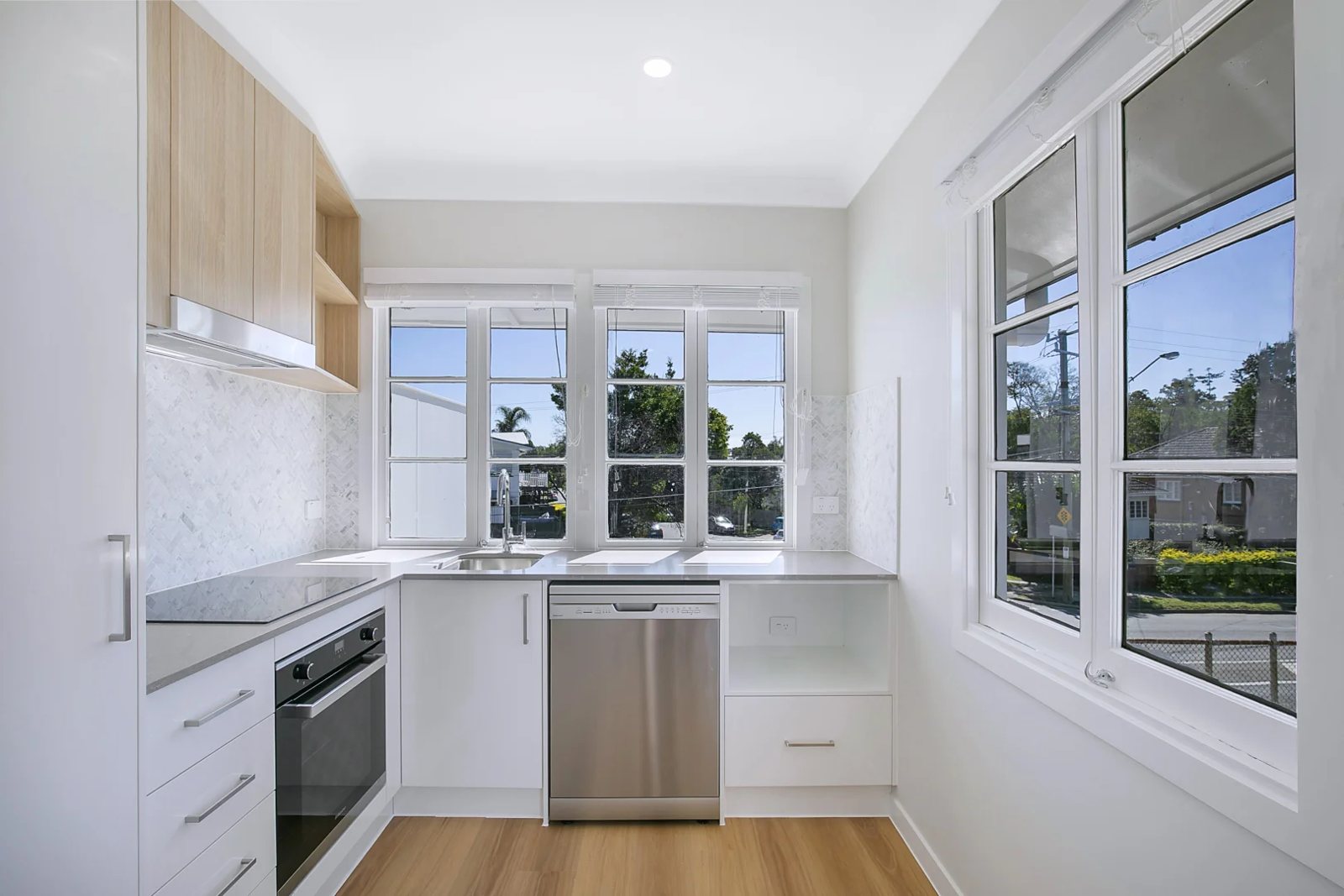 Galley kitchen with herringbone splashback under casement windows