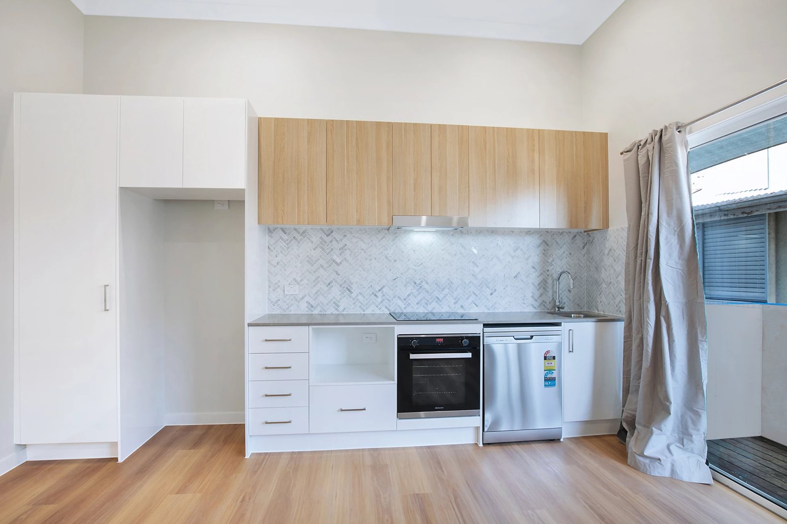 Single-wall kitchen with timber-look overheads and herringbone tiles