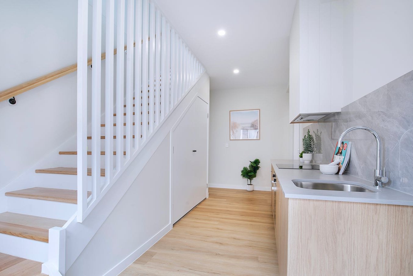 Entry with white slatted stair balustrade, timber treads and kitchenette